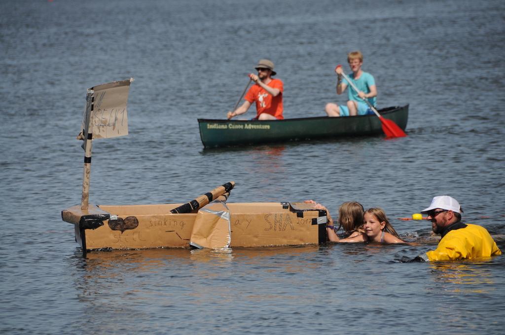 zwei Mädchen schieben Pappboot an Land